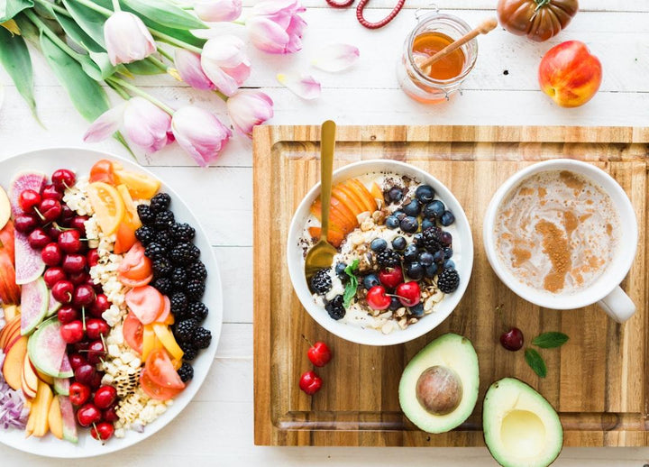 Colorful healthy breakfast with berries, avocado, fresh fruit, and coffee on a wooden board