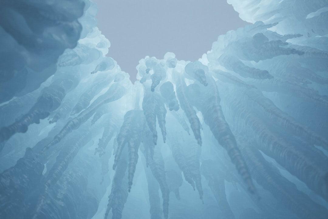 Upward view of tall blue icicles forming a striking ice cave structure against the sky