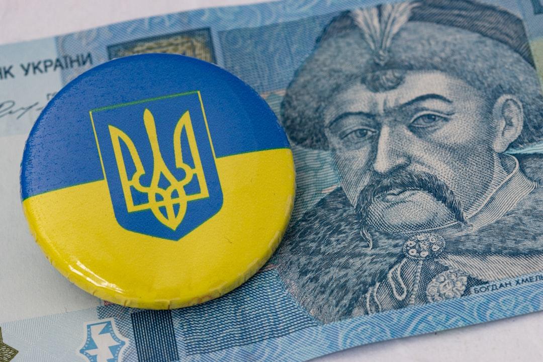 Ukrainian trident emblem button on blue and yellow background atop currency note